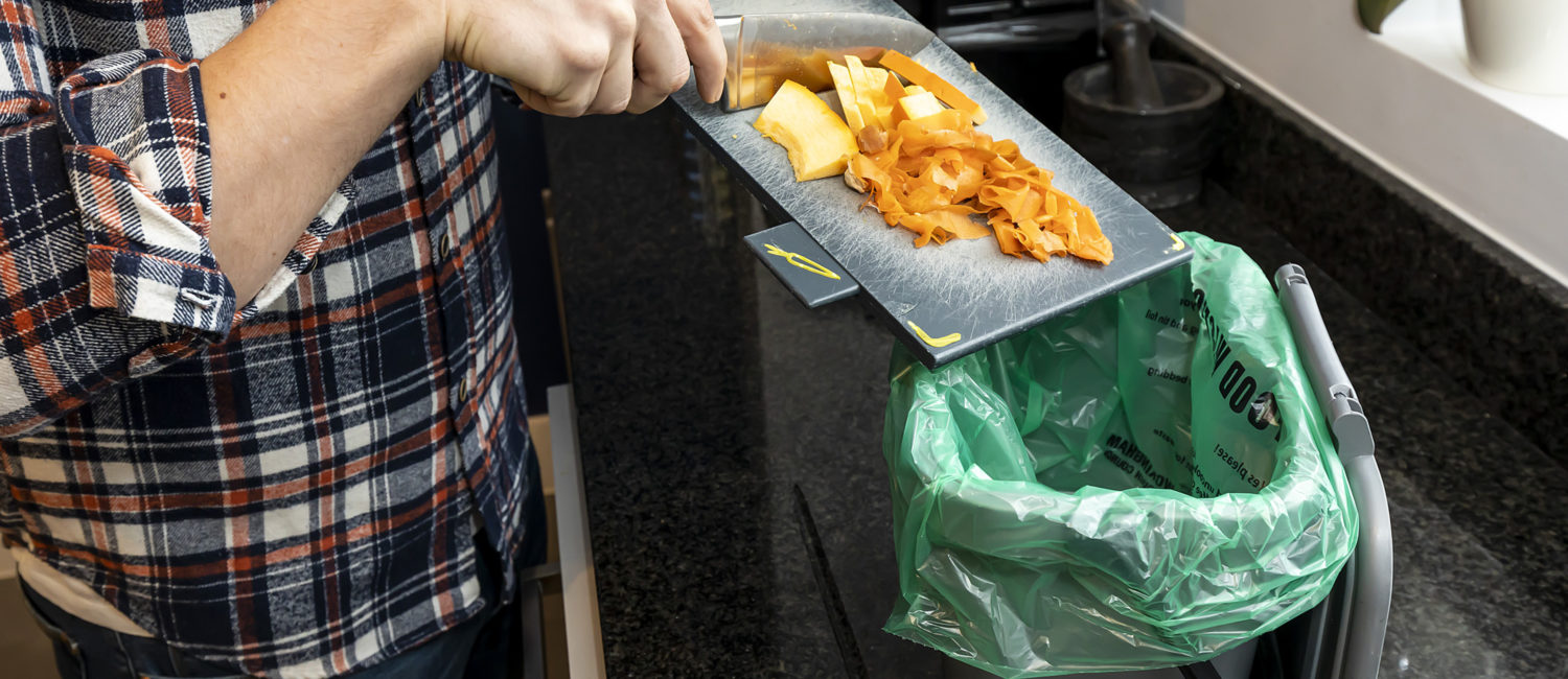 Person scraping food waste in to a caddy
