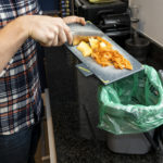 Person scraping food waste in to a caddy