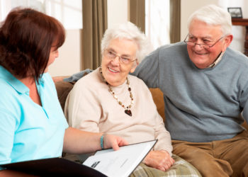 Friendly person speaking to smiling elderly man and woman