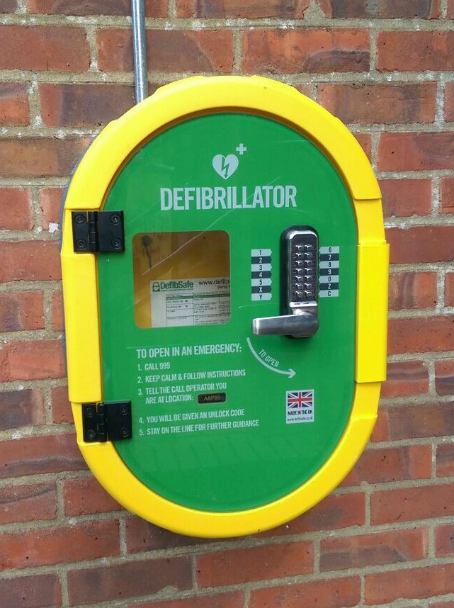 yellow and green defibrillator cabinet on a wall