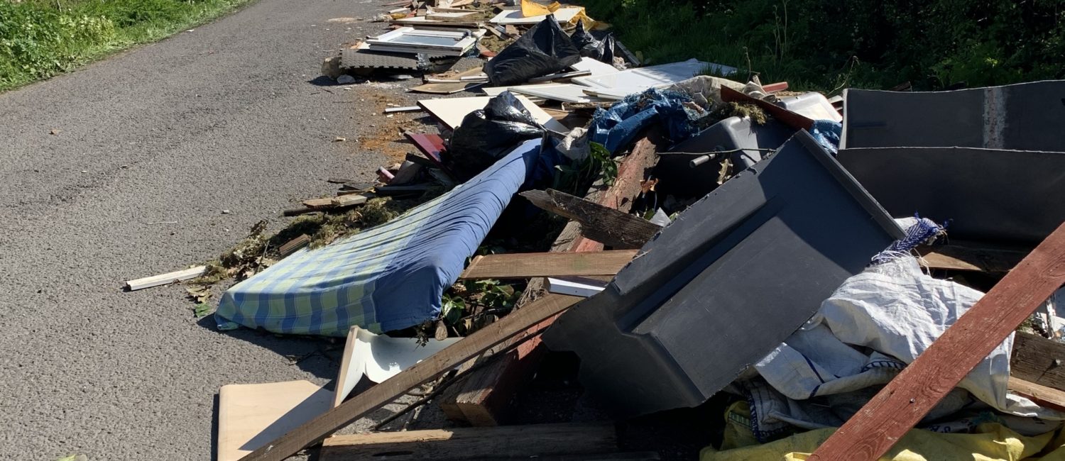 Heap of flytipping by a road including mattress and planks