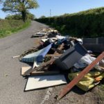 Heap of flytipping by a road including mattress and planks