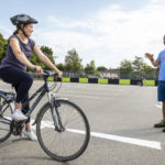 Lady on bicycle with man giving instructions