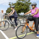 Two ladies on bicycles with lady giving instructions