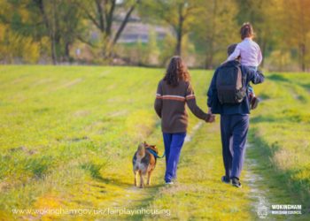 man and woman with dog and small child walking through countryside