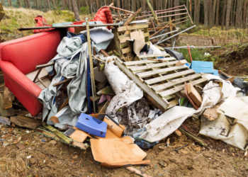 Pile of flytipped wasted including orange sofa and pallets and metal gate