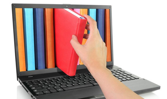 Laptop with hand taking a red book out of the screen