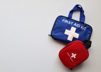 Large blue bag with first aid kit written on it and smaller red first aid kit